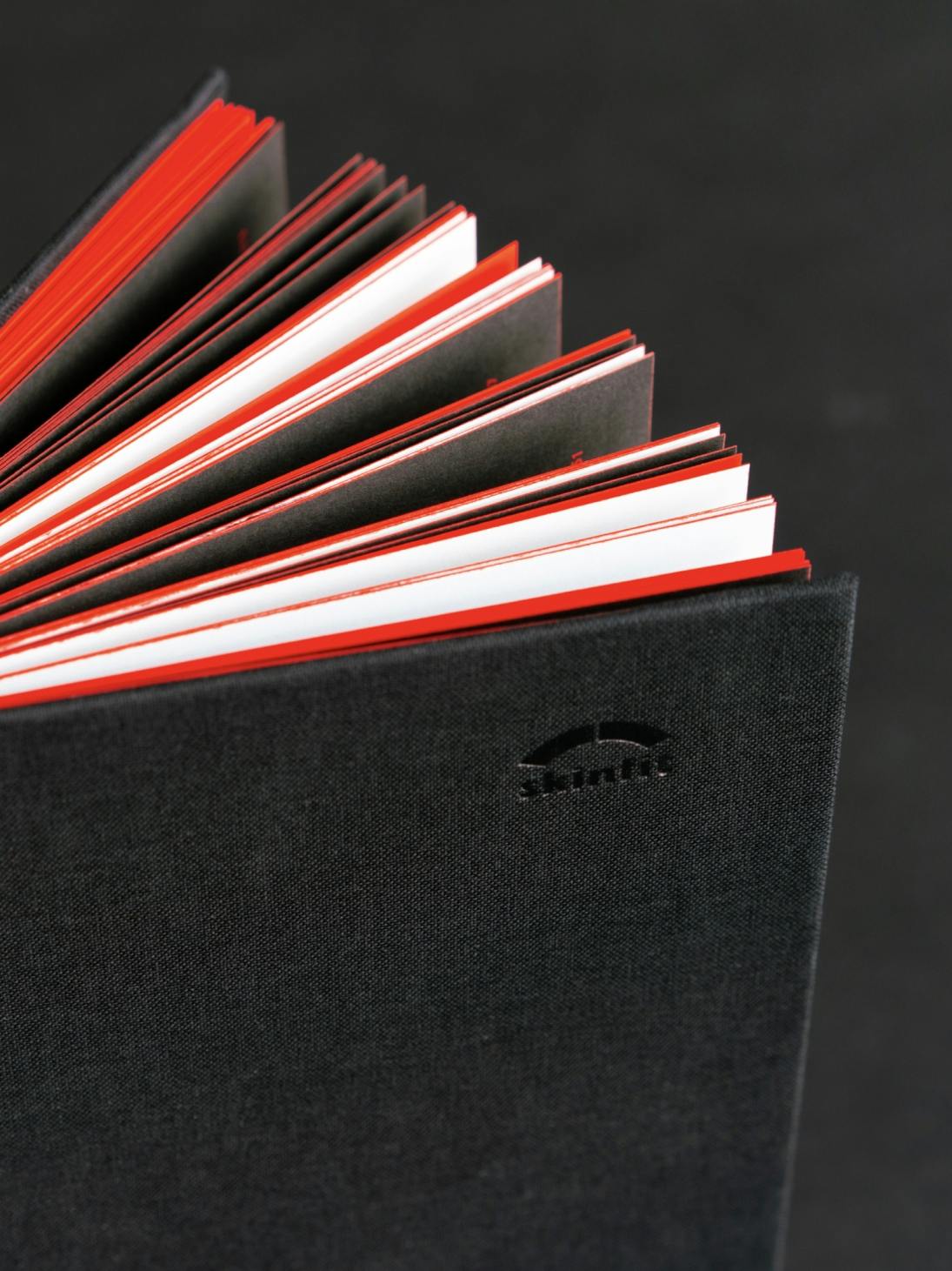 Detailansicht des Umschlags vom skinfit brand book, schwarzer Leinenumschlag mit Blindprägung und roter Farbschnitt © gm gobiq
