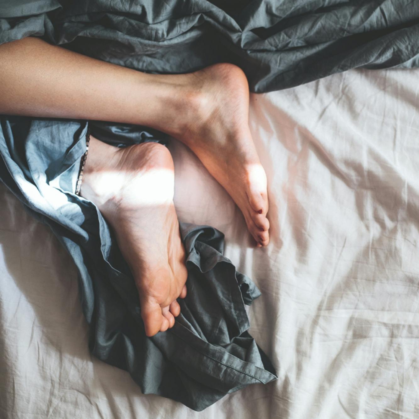 Detailaufnahme: nackte Frauenfüße auf einem Bett in gemütlicher Pose © gobiq