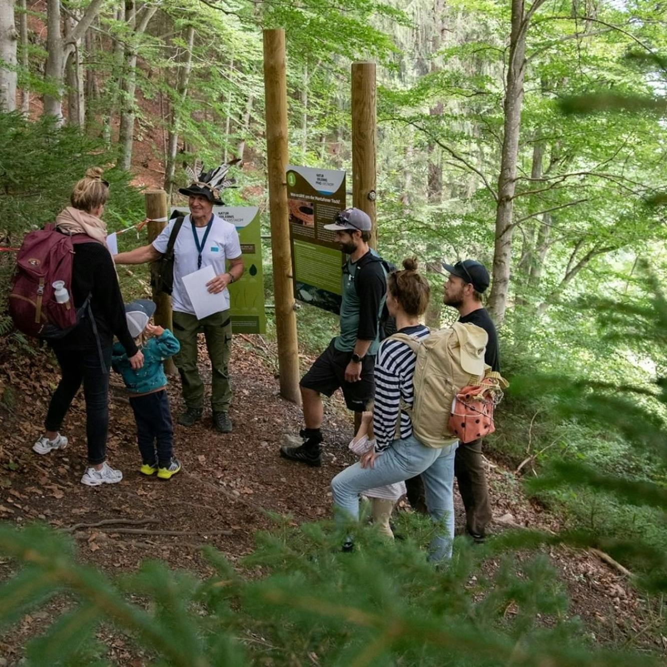 Gruppe von Personen steht im Wald zusammen und hört dem Wanderführer zu © maray festival