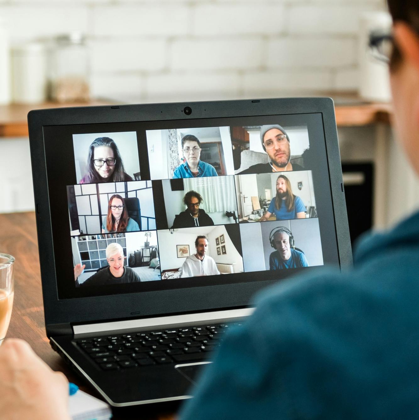 Mann sitzt vor einem Laptop und nimmt an einem Online Meeting teil mit vielen anderen Menschen auf dem Bildschirm © good matters