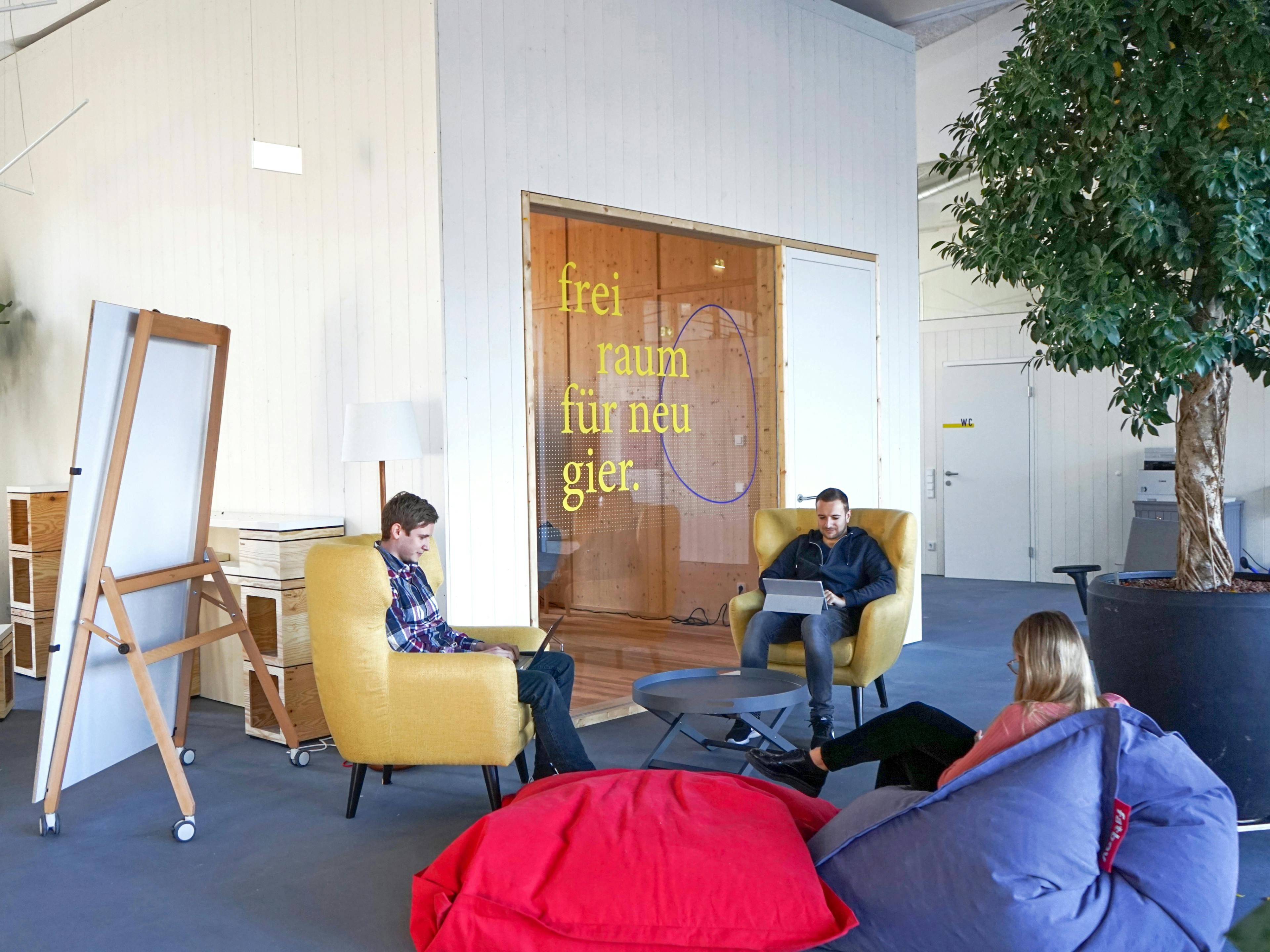 Foto eines Innenraumes der Postgarage mit Personen auf gemütlichen Sesseln und einer gestalteten Fensterbeklebung mit Designelementen der Postgarage © gobiq